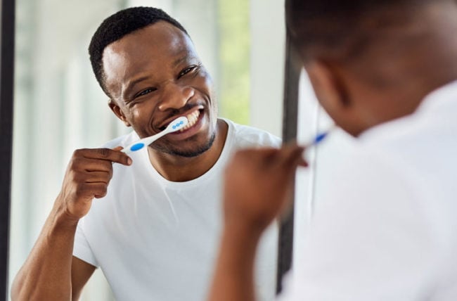 Inimene peseb hambaid vannitoas peeglisse vaadates.