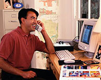 Pilt mehest, kes töötab arvutiga ja räägib telefoniga